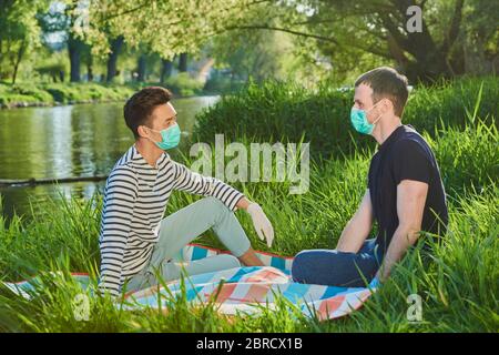 Due uomini con maschere in un prato vicino a un fiume, crisi di Corona, Danubio, Baviera, Germania Foto Stock