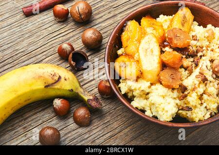 Porridge di miglio con banane e noci su tavola di legno Foto Stock