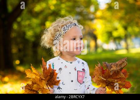 Felice bambina con foglie autunnali di acero in mano, Austria superiore, Austria Foto Stock