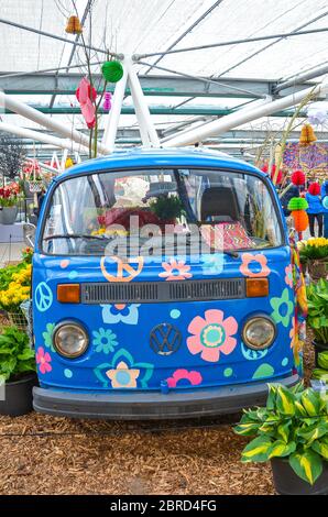 Keukenhof, Lisse, Paesi Bassi - 28 aprile 2019: Persone che camminano all'interno di una casa espositiva nei giardini di Keukenhof. Furgone hippie con simboli hippies, fiori colorati. Foto verticale. Foto Stock