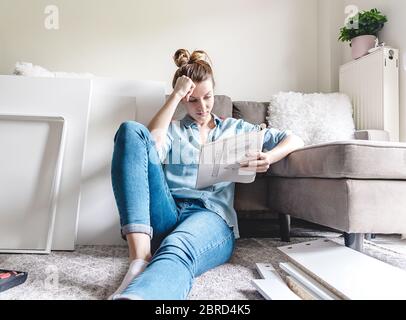 Giovane donna che monta nuovi mobili per la casa Foto Stock