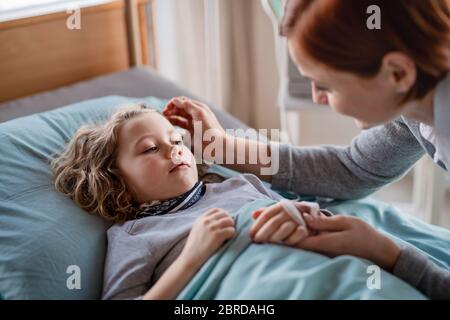 Madre che si prende cura di visitare la figlia di bambina in letto in ospedale. Foto Stock