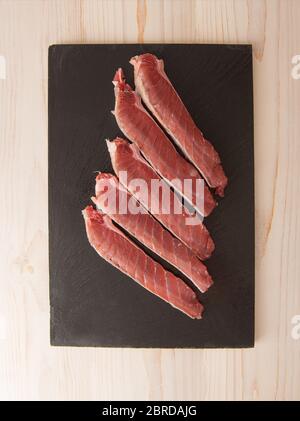 Filetto di tonno crudo su sfondo scuro. Foto Stock