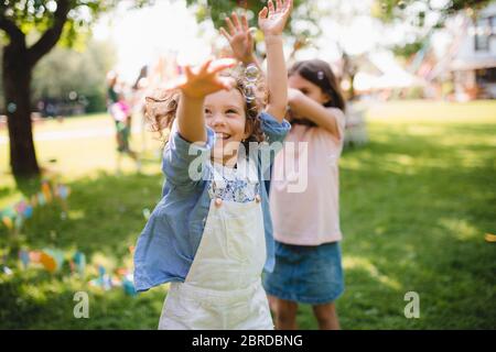 Bambini piccoli in piedi all'aperto in giardino in estate, giocando. Foto Stock