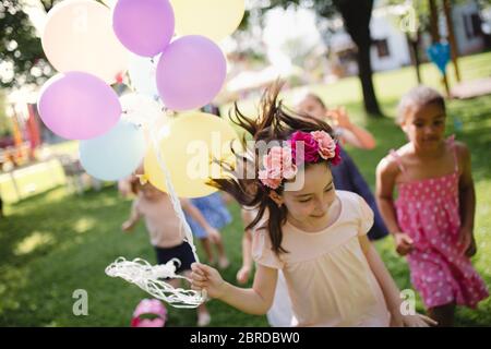 Bambini piccoli che corrono all'aperto in giardino in estate, giocando. Foto Stock
