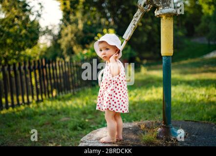 Una bambina che si trova all'aperto in giardino in estate. Foto Stock