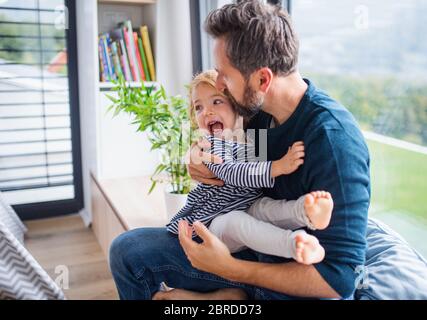 Giovane padre allegro con piccola figlia al chiuso in camera da letto giocando. Foto Stock