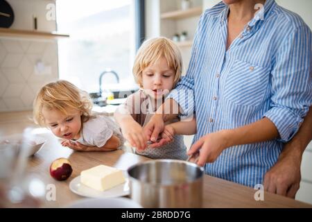 Giovane famiglia con due bambini piccoli in cucina, preparando il cibo. Foto Stock