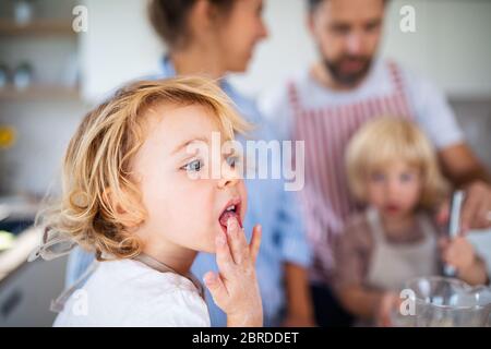 Piccola ragazza con famiglia al coperto in cucina, cucina. Foto Stock