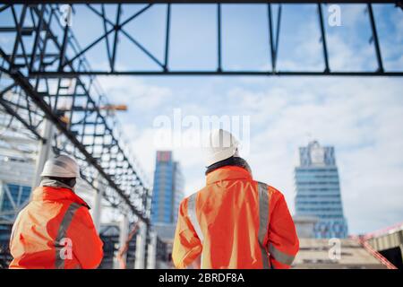 Vista posteriore dei tecnici che si alzano all'aperto sul cantiere. Foto Stock