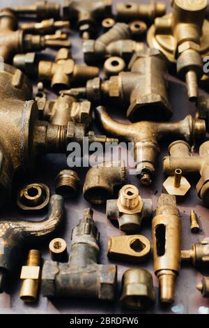 Ottone rottame metallo: Rubinetti, raccordi a T, tappi e vari componenti idraulici, ricambi. Sullo sfondo di un foglio di rame. Primo piano. Foto Stock