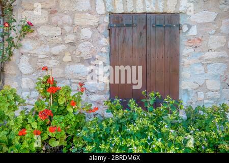 Persiane chiuse in legno sulla parete di pietra di un antico casale francese in un villaggio rurale in Provenza, Francia. Foto Stock