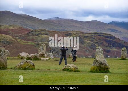Il giovane uomo scatta foto sul cellulare di giovani donne e cani attraenti a Castlerigg Stone Circle nel distretto inglese del lago, Regno Unito Foto Stock