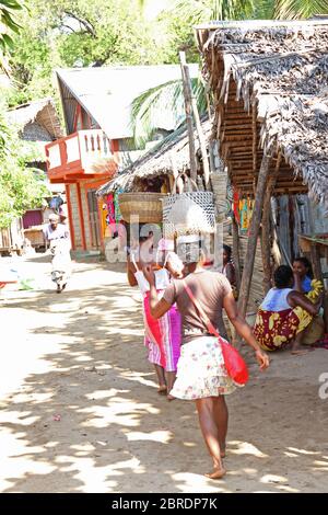 Donne che camminano con i cestini sulla testa in strada nel villaggio di Ampangorinana Nosy Komba Island, Madagascar. Foto Stock