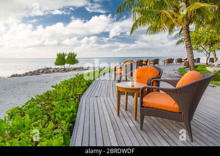 Tavolo al ristorante sulla spiaggia. Elegante bar esterno sul mare con sedie e tavoli su terrazza in legno Foto Stock