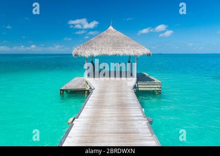 Splendido paesaggio tropicale tramonto con ville in legno sulle acque dell'Oceano Indiano, Maldive Island. Lussuosa spa sull'acqua, mare tropicale blu Foto Stock