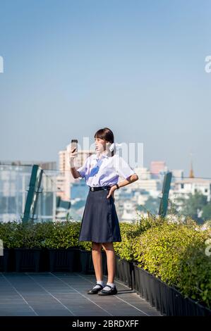 Un grazioso studente thailandese universitario prende un selfie sul balcone del Centro commerciale Iconsiam, Bangkok. Foto Stock