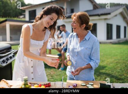 Ritratto di famiglia multigeneration all'aperto su barbecue giardino, grigliatura. Foto Stock