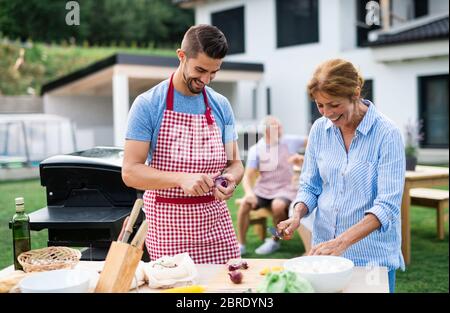 Ritratto di famiglia multigeneration all'aperto su barbecue giardino, grigliatura. Foto Stock