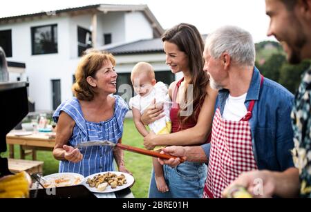 Ritratto di famiglia multigeneration all'aperto su barbecue giardino, grigliatura. Foto Stock