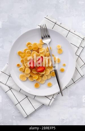 Minuscoli cereali con pancake. Colazione fatta in casa con lamponi, marmellata e succo su sfondo grigio Foto Stock