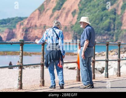 Sidmouth, East Devon, Regno Unito. 21 Maggio 2020. Tempo in Gran Bretagna: Una coppia ammira la vista dalla spianata in una giornata gloriosamente calda e soleggiata presso la pittoresca cittadina regency di Sidmouth. Il sole caldo e bruciante è previsto per continuare nel fine settimana di festa della banca. Credit: Notizie dal vivo di DWR/Alamy Foto Stock