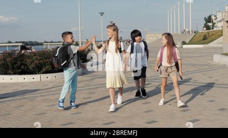 Bambini della scuola infantile che vanno a scuola con zaini e danno l'alig Foto Stock