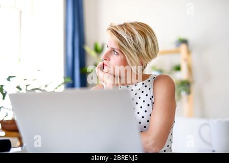 Triste giovane donna d'affari con il laptop in casa in ufficio, lavorando. Foto Stock