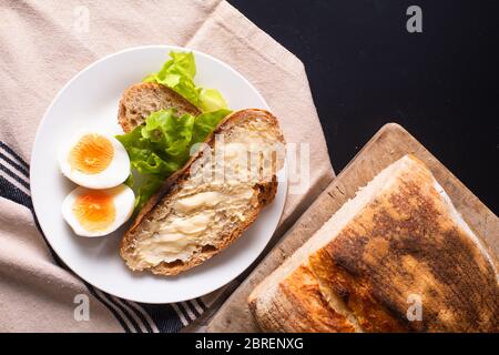 Concetto di cibo sano e salutare artigianale biologico artigianale pane e uovo bollito in piatto bianco con spazio per la copia Foto Stock