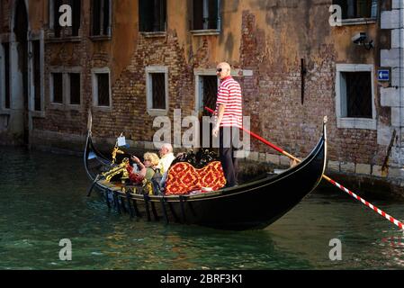 Venezia, Italia - 18 maggio 2017: Gondola con gente naviga su un vecchio canale a Venezia. La gondola è un mezzo di trasporto turistico più attraente di Venezia. Romantico Foto Stock