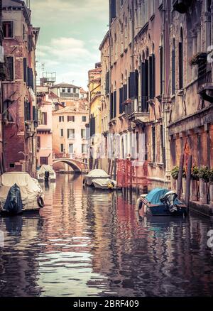 Vecchia strada con barche parcheggiate, Venezia, Italia. Bella vista verticale del canale di Venezia con riflessi in acqua. Edifici d'epoca e paesaggio urbano di Ven Foto Stock