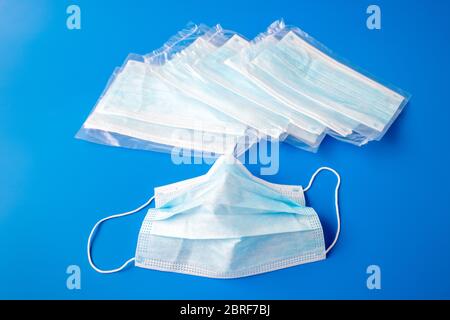 Usato monouso e nuovo in confezione maschera medica su a. sfondo blu Foto Stock