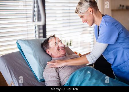 Un operatore sanitario e un paziente anziano in ospedale, parlando. Foto Stock