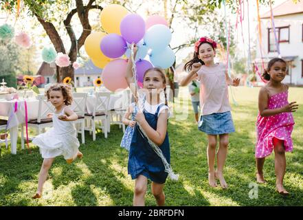 Bambini piccoli all'aperto in giardino in estate, giocando con palloncini. Foto Stock