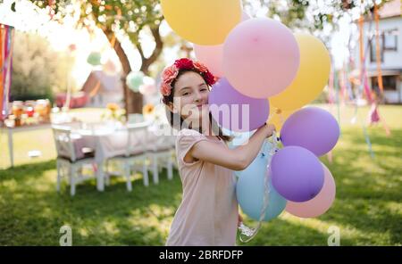Piccola ragazza all'aperto in giardino in estate, giocando con palloncini. Foto Stock