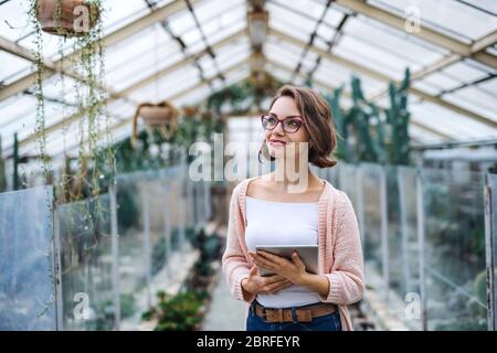 Donna ricercatore in serra, utilizzando tablet. Foto Stock