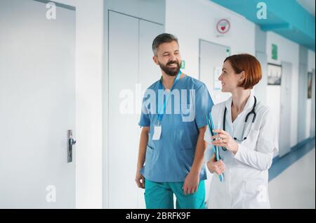 Ritratto di uomo e donna dottore che cammina in ospedale, parlando. Foto Stock