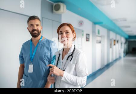 Ritratto di uomo e donna dottore che cammina in ospedale, guardando la macchina fotografica. Foto Stock