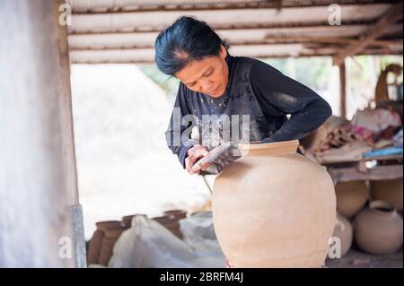 Una donna che forma una pentola di argilla usando un pipistrello di legno. Provincia di Kampong Chhnang, Cambogia, Sud-est asiatico Foto Stock