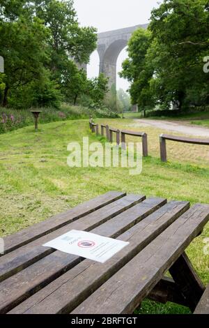 Avviso del Consiglio pinzato su un tavolo da picnic in un parco di campagna vuoto che vieta l'uso del tavolo a causa delle norme di salute e sicurezza del Covid 19. Foto Stock