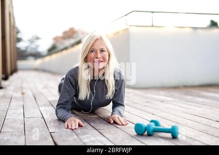 Una donna anziana che fa l'esercitazione all'aperto, che si allunga. Foto Stock