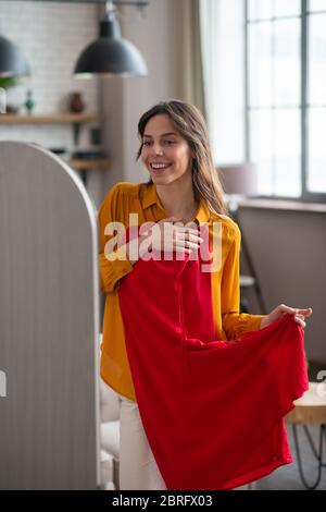 Sorridente giovane ragazza che prova un nuovo vestito e che guarda eccitato Foto Stock