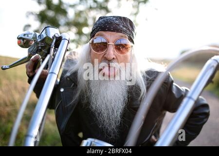 Uomo anziano con moto in campagna, divertendosi. Foto Stock
