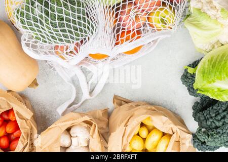 Concetto di shopping ecologico senza plastica, frutta di verdura in cotone mesh bianco e sacchetti di carta su tavolo da cucina bianco, vista dall'alto, messa a fuoco selettiva Foto Stock