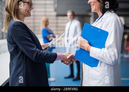 Medico che parla con il rappresentante di vendita farmaceutico, scuotendo le mani. Foto Stock