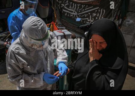 Baghdad, Iraq. 21 Maggio 2020. Un operatore sanitario del Ministero della Salute indossare tuta protettiva prende un campione di sangue da una donna durante un esame sul campo per eseguire il coronavirus (COVID-19) test per i cittadini nel quartiere sobborgo Sadr City a Baghdad. Credit: Ameer al Mohammedaw/dpa/Alamy Live News Foto Stock