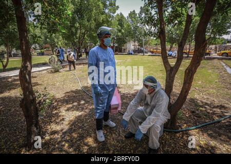 Baghdad, Iraq. 21 Maggio 2020. Gli operatori sanitari del Ministero della Salute indossare tute protettive si riposano durante un esame sul campo per eseguire il test del coronavirus (COVID-19) per i cittadini nel quartiere sobborgo Sadr City a Baghdad. Credit: Ameer al Mohammedaw/dpa/Alamy Live News Foto Stock