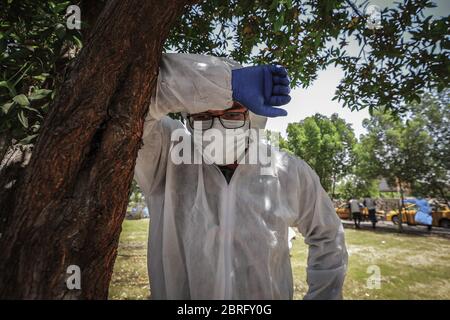 Baghdad, Iraq. 21 Maggio 2020. Un operatore sanitario del Ministero della Salute indossare tuta protettiva si riposa durante un esame sul campo per eseguire il test del coronavirus (COVID-19) per i cittadini nel quartiere sobborgo Sadr City a Baghdad. Credit: Ameer al Mohammedaw/dpa/Alamy Live News Foto Stock