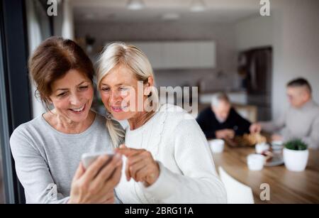 Gruppo di amici senior a casa, utilizzando gli smartphone. Foto Stock