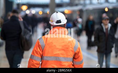 Operaio di manutenzione che cammina attraverso una stazione ferroviaria in Inghilterra, Regno Unito. Foto Stock